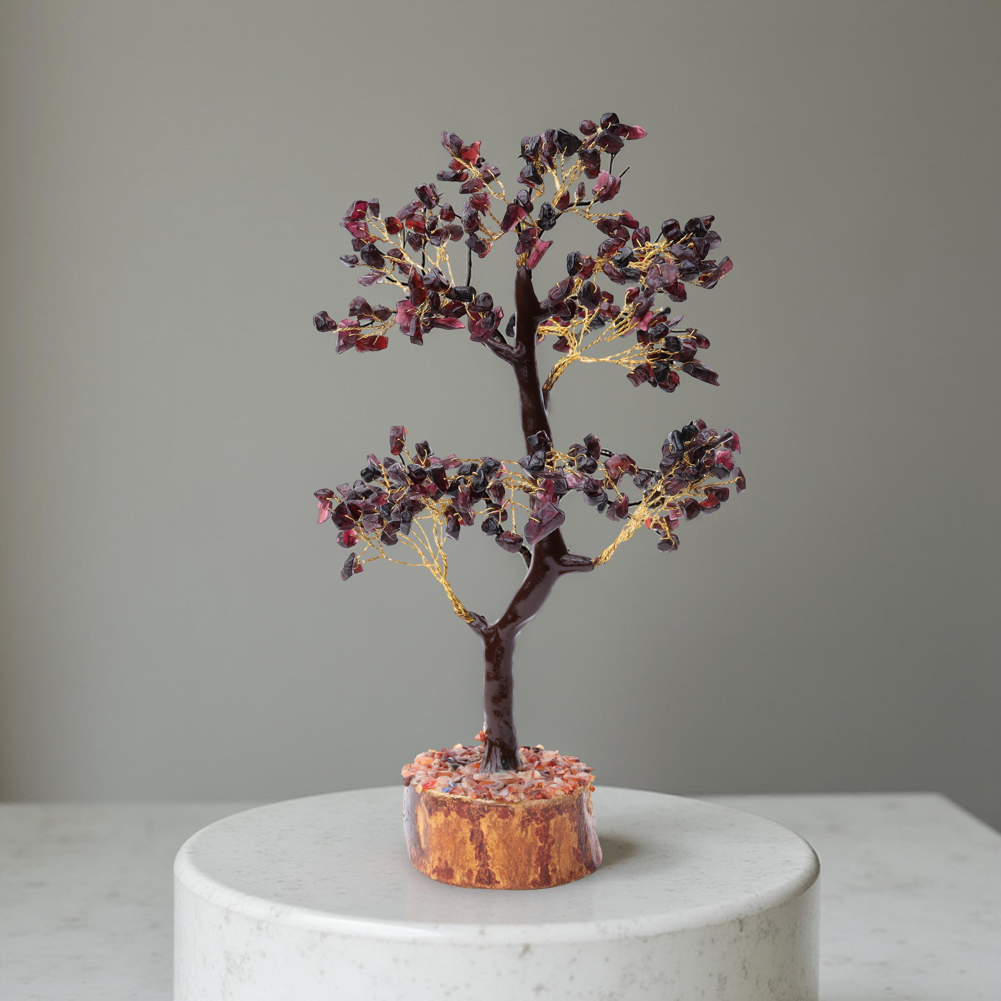 AstroViz deep red garnet stone chip decorative tree on natural wood slice base displayed on white marble pedestal, grey background--3