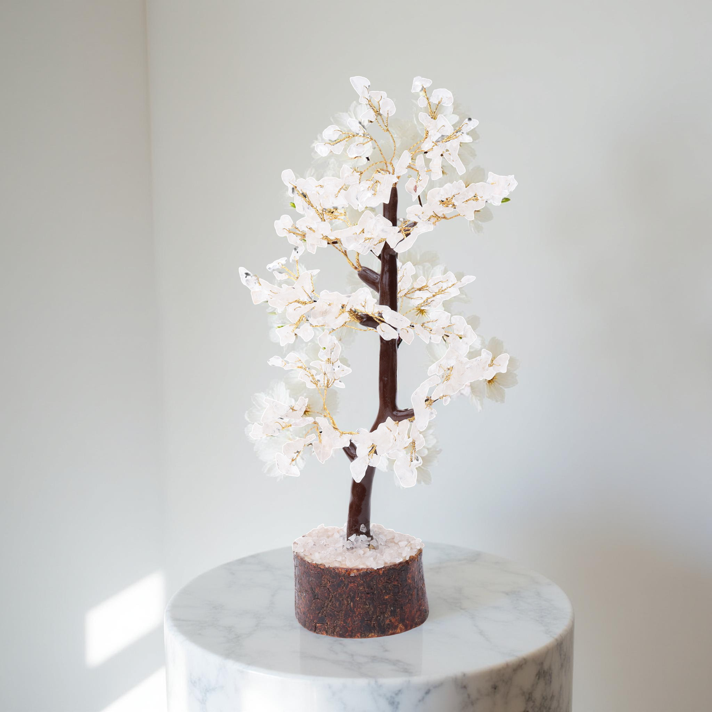 AstroViz handcrafted white moonstone gemstone chip decorative blossom tree with sculptural looping trunk placed on white marble pedestal in bright white interior setting
