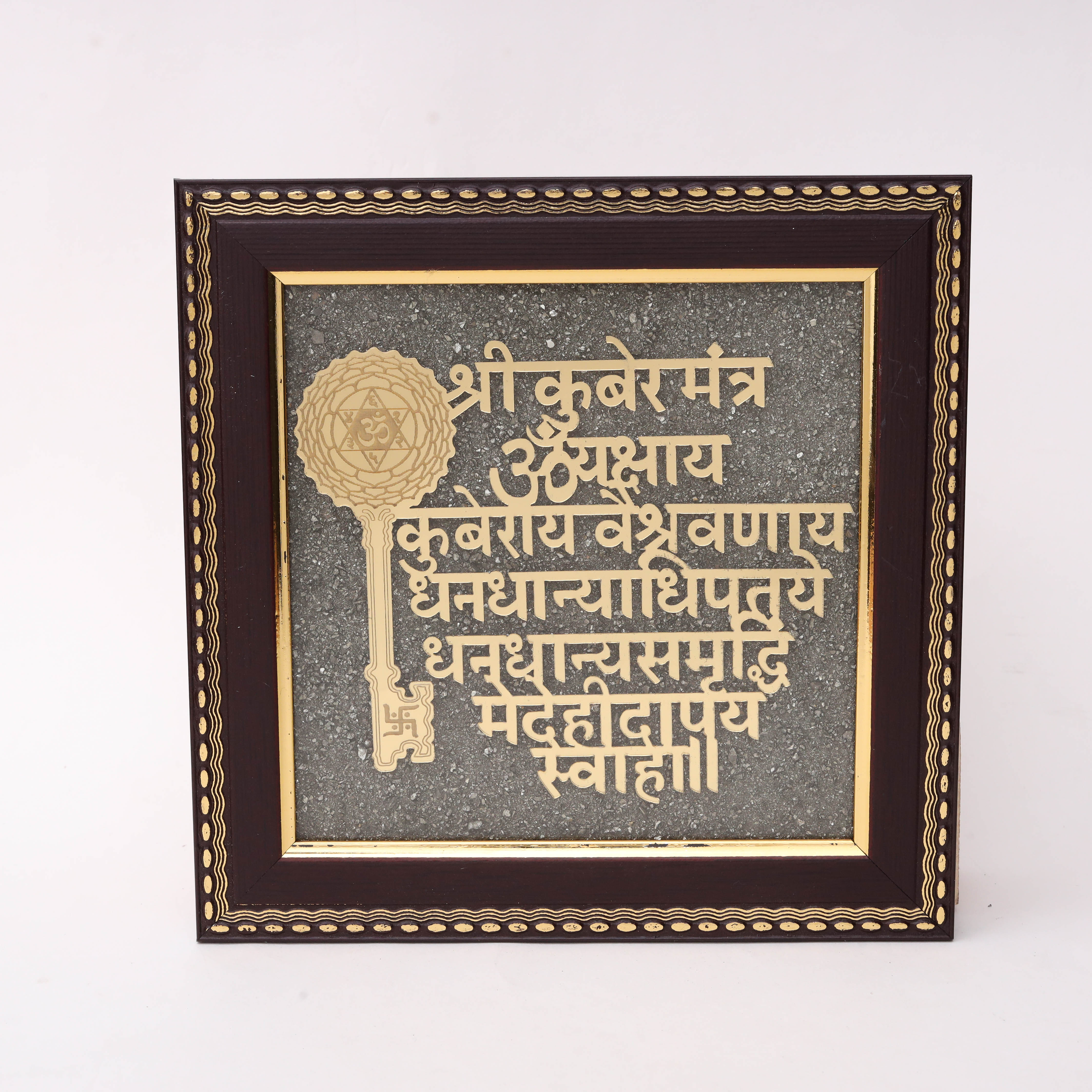 Gold laser-cut Shri Kuber Mantra Sanskrit text with decorative Kuber Key symbol featuring Shatkona Om and Swastik on charcoal stone texture background in dark wood frame
--1