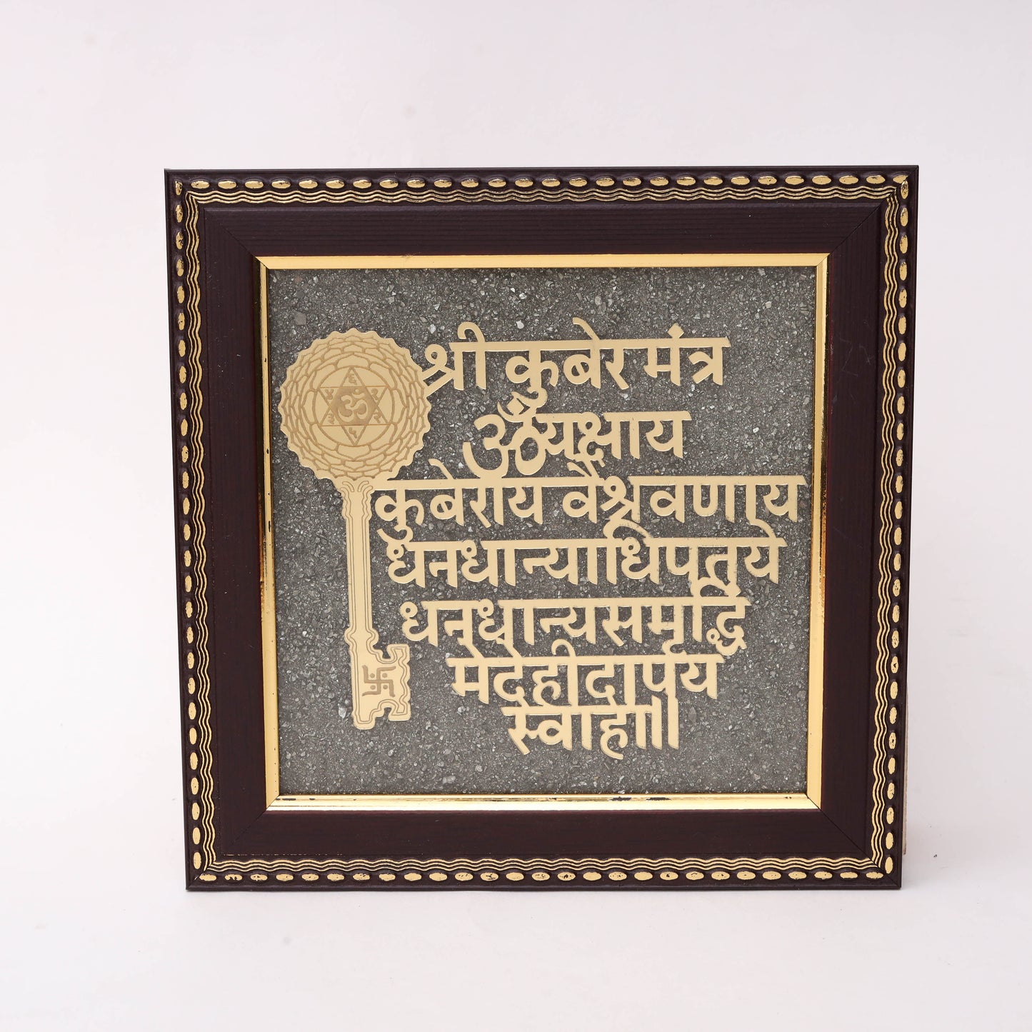 Gold laser-cut Shri Kuber Mantra Sanskrit text with decorative Kuber Key symbol featuring Shatkona Om and Swastik on charcoal stone texture background in dark wood frame
