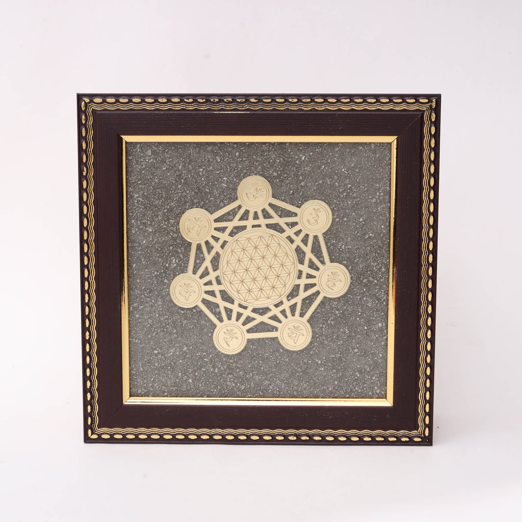 Gold laser-cut Metatron's Cube sacred geometry with Flower of Life center and seven Sanskrit symbol medallions on charcoal stone texture background in dark wood decorative frame