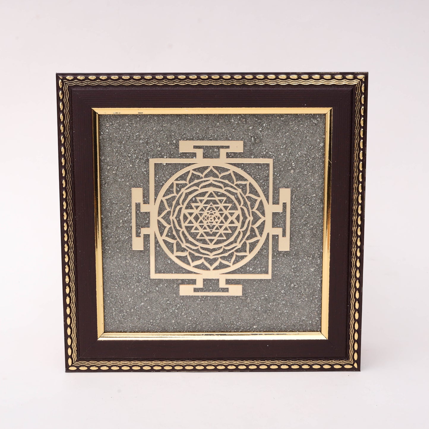 AstroViz Sri Yantra gold-tone laser-cut motif on grey stone chip background in dark brown ornate embossed wooden frame
