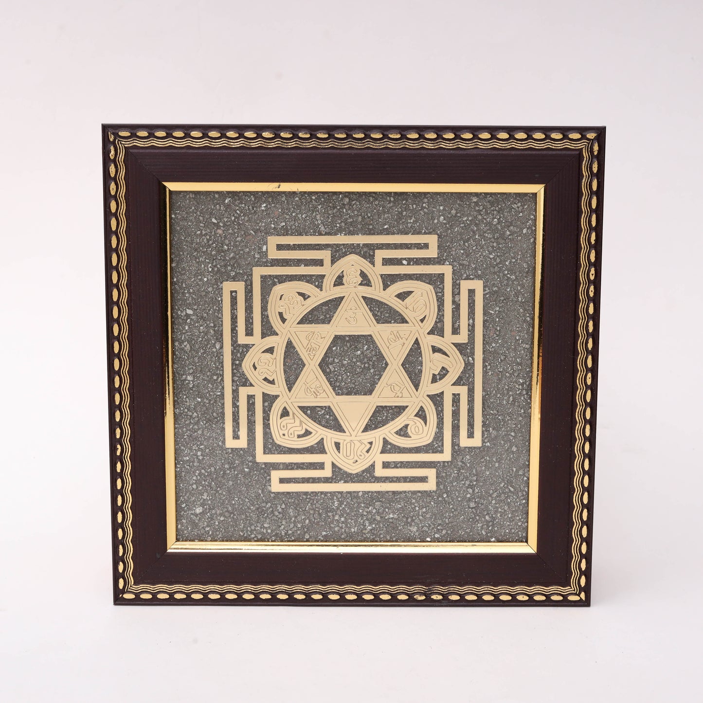 AstroViz Surya Yantra gold-tone metallic motif on textured grey stone background in a dark brown ornate wooden frame.