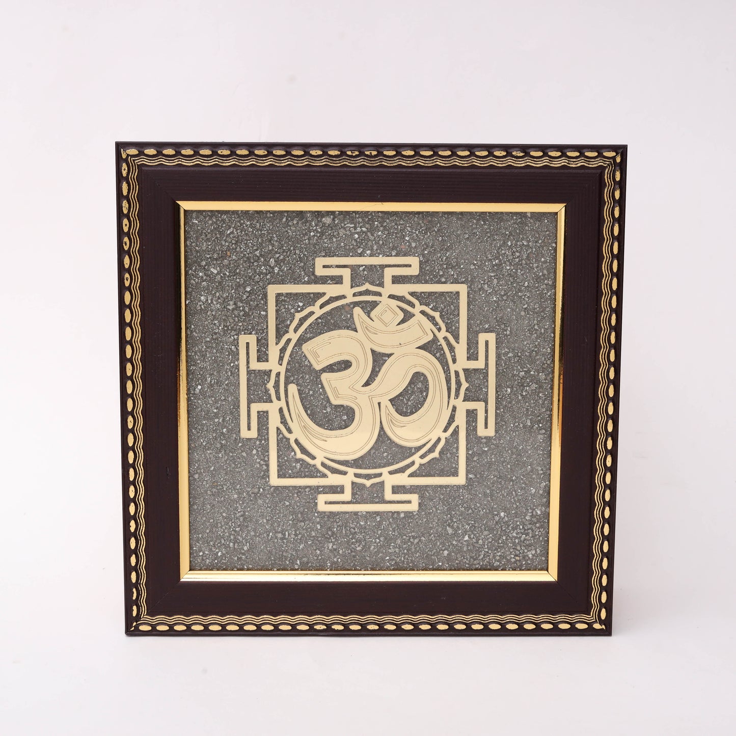 AstroViz Om gold-tone laser-cut motif on textured grey stone chip background in a dark brown ornate embossed wooden frame.